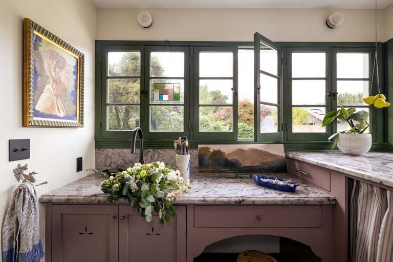 laundry room with mauve cabinets and green windows