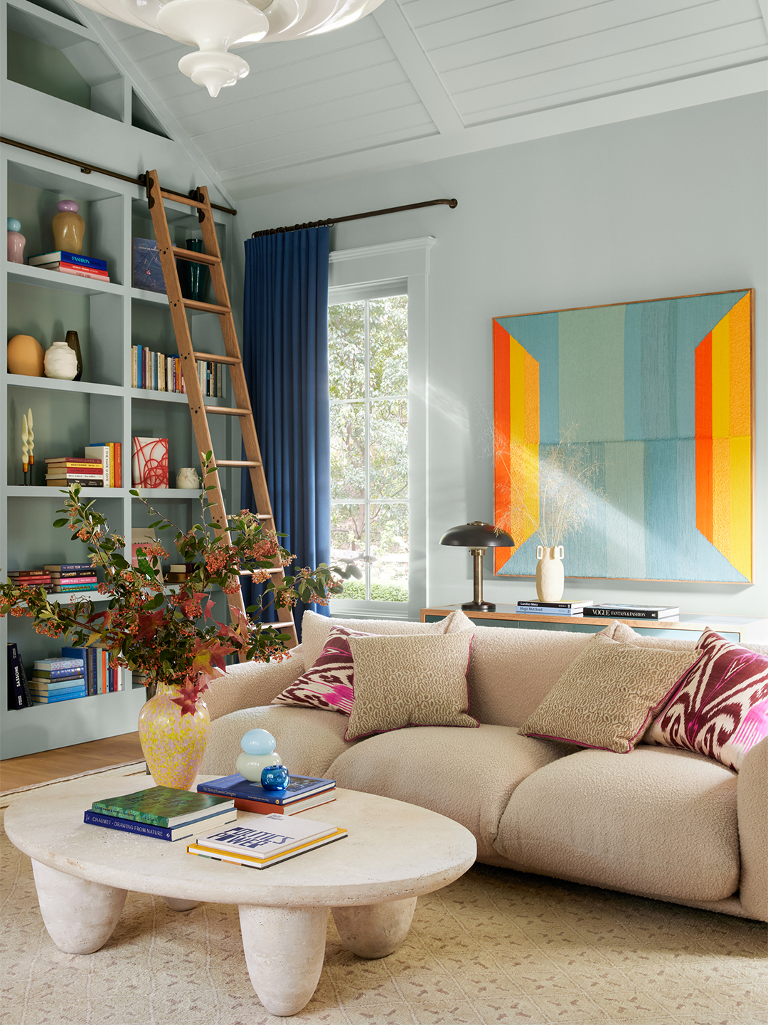 living room with library ladder and tall bookshelves