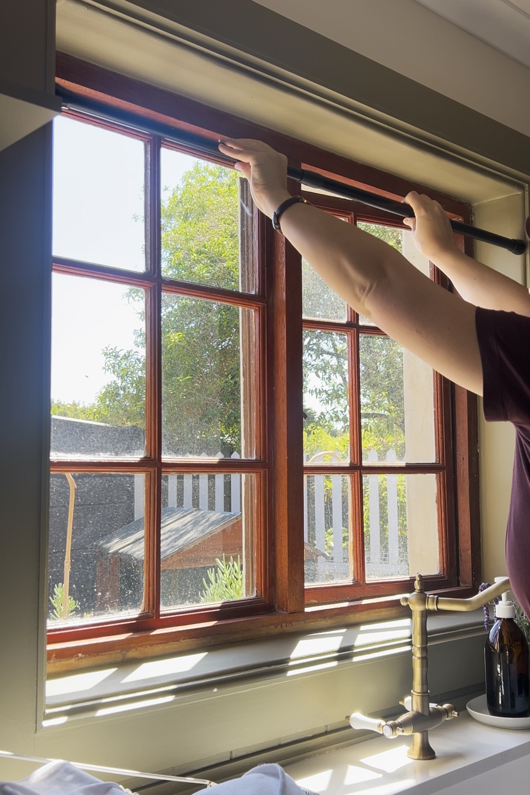 woman measuring a window using a tension rod