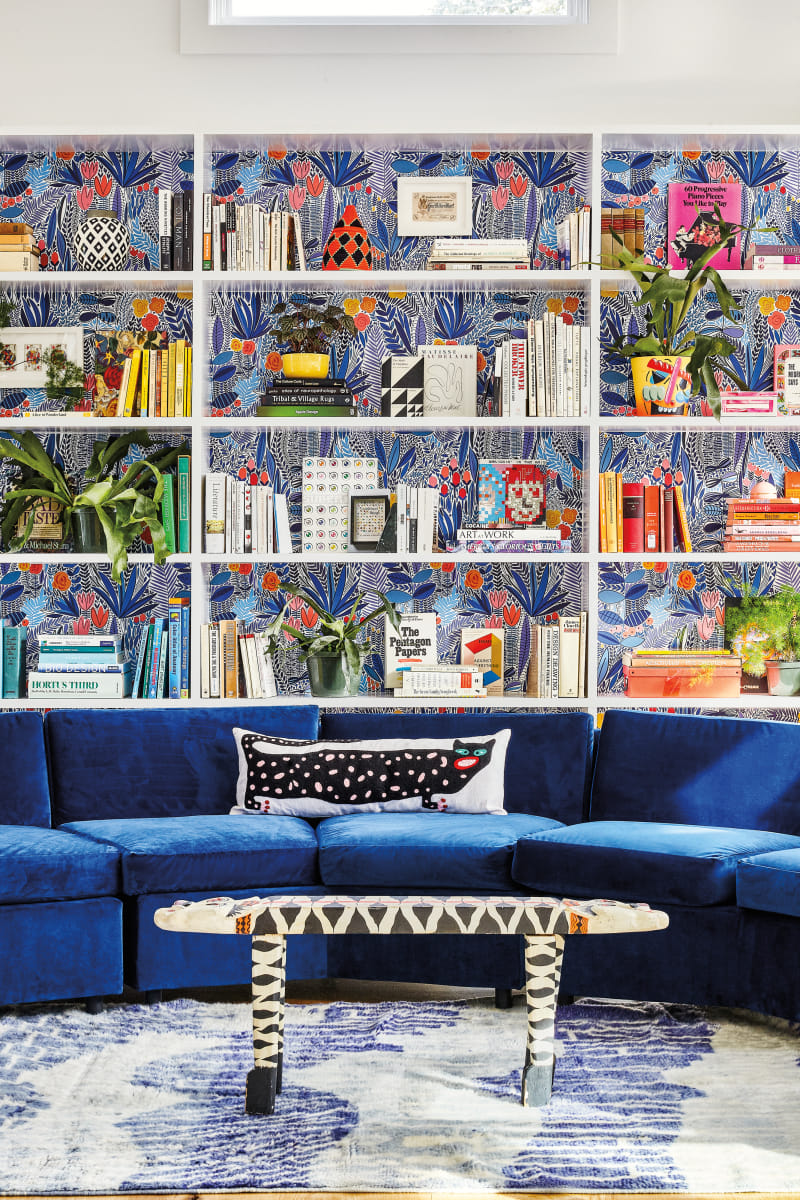 blue sofa and white shelves with wallpapered background in living room