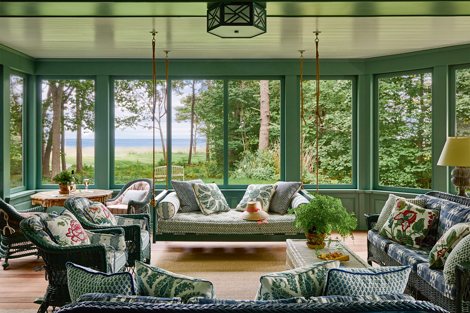 green sunroom with views of a lake and hanging daybed