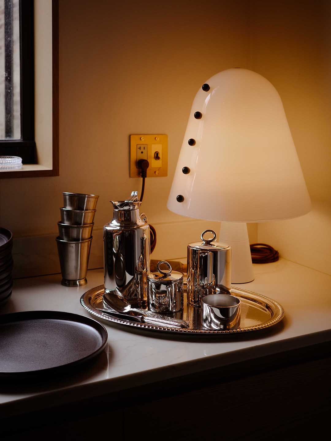silver barware next to frosted glass table lamp