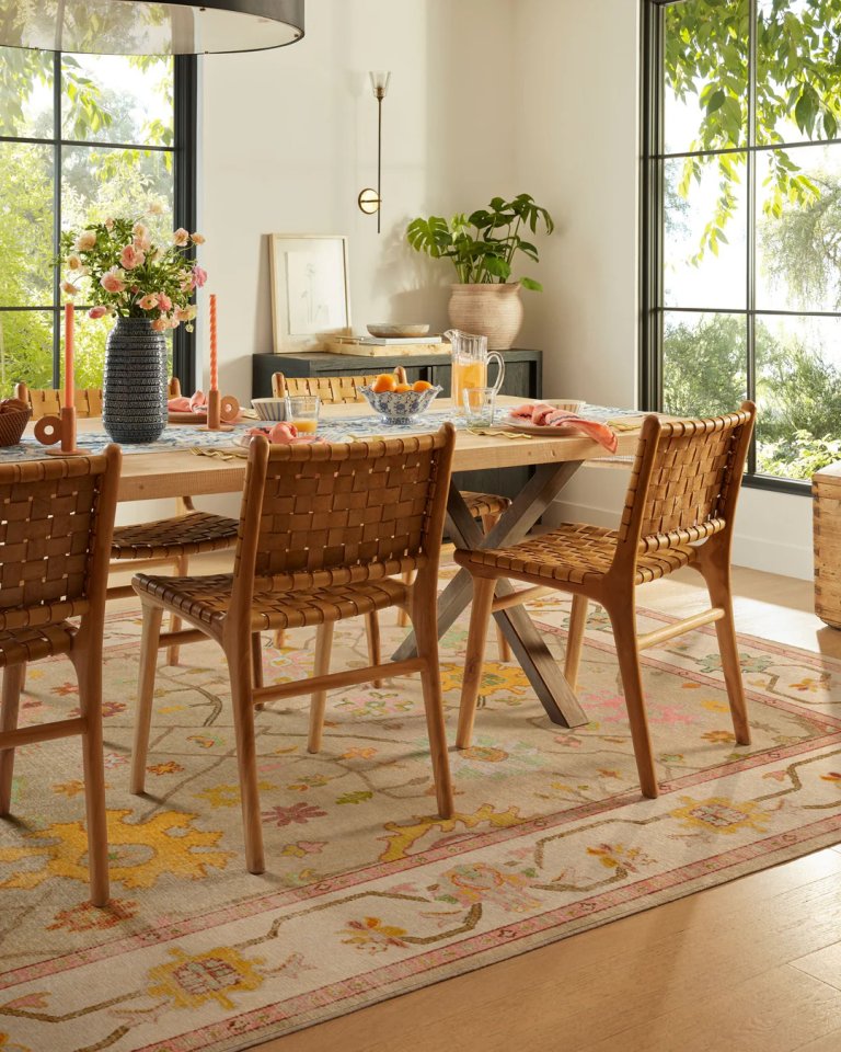 Sunlit dining room with cream colored rug underneath dining table.