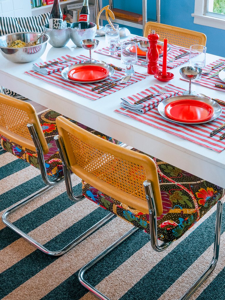 Colorful table setting with red plates and striped napkins.