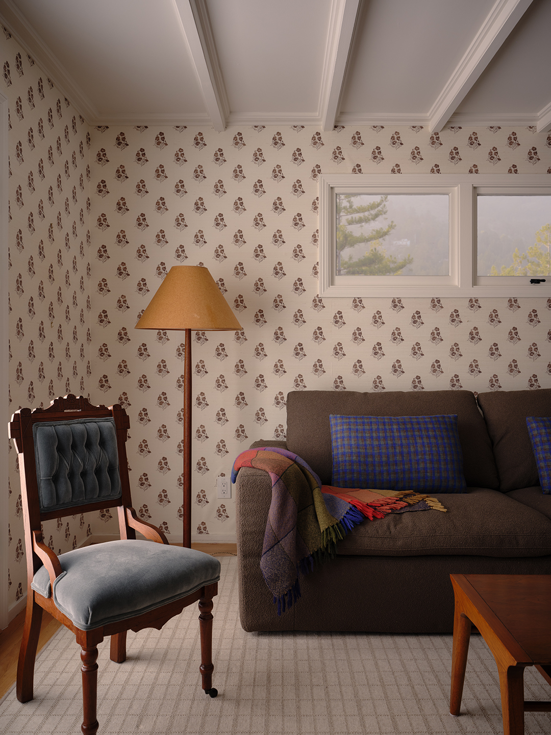 wallpapered room with brown sofa and wood chair