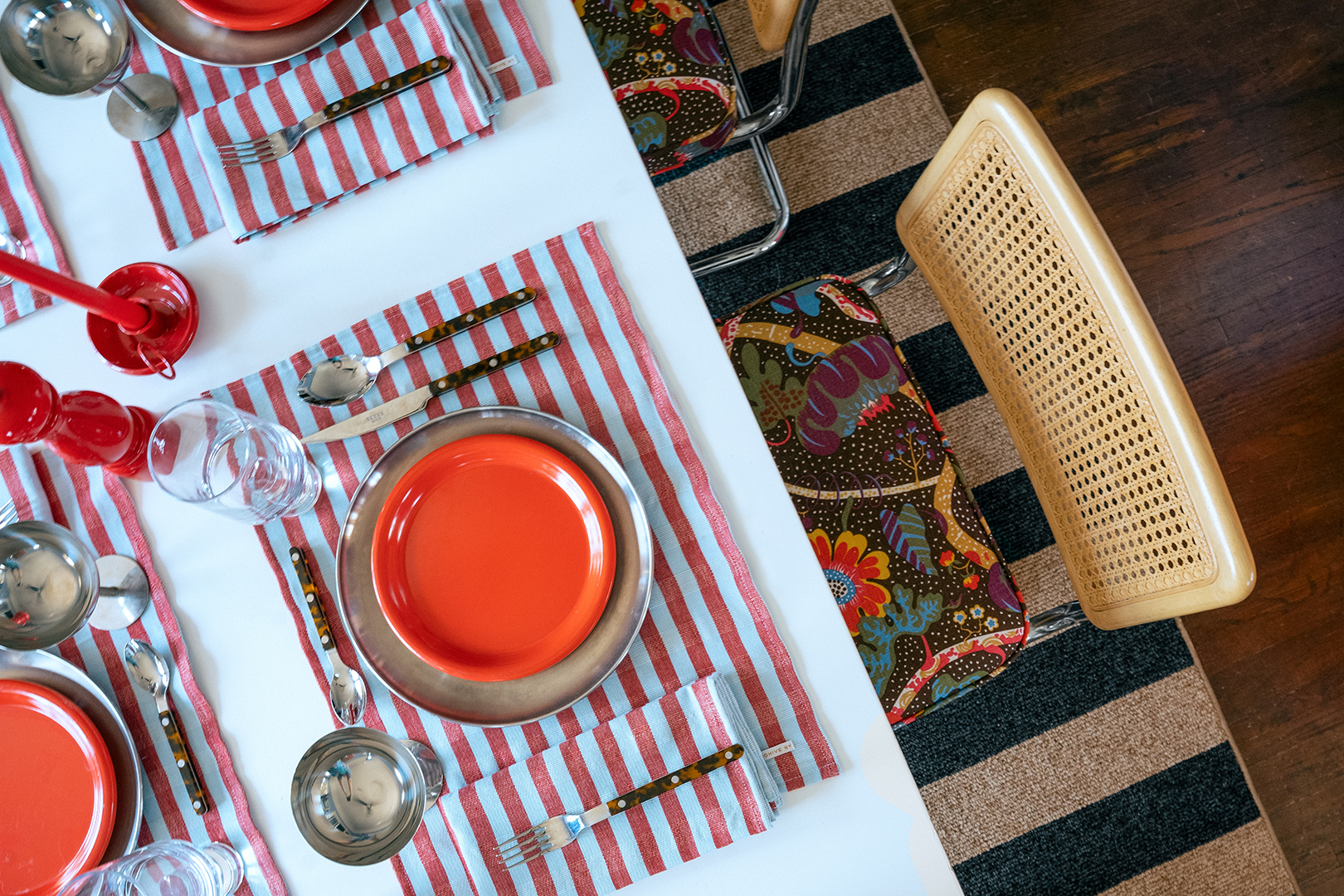 Overhead shot of colorful dining table with red plates and striped placemats.