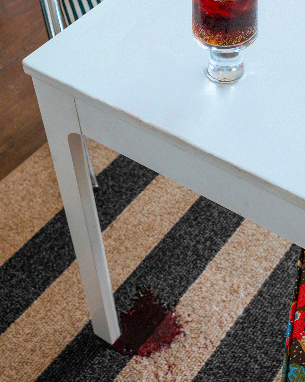 Gif of red wine being spilled on striped rug and hand blotting stain clean.