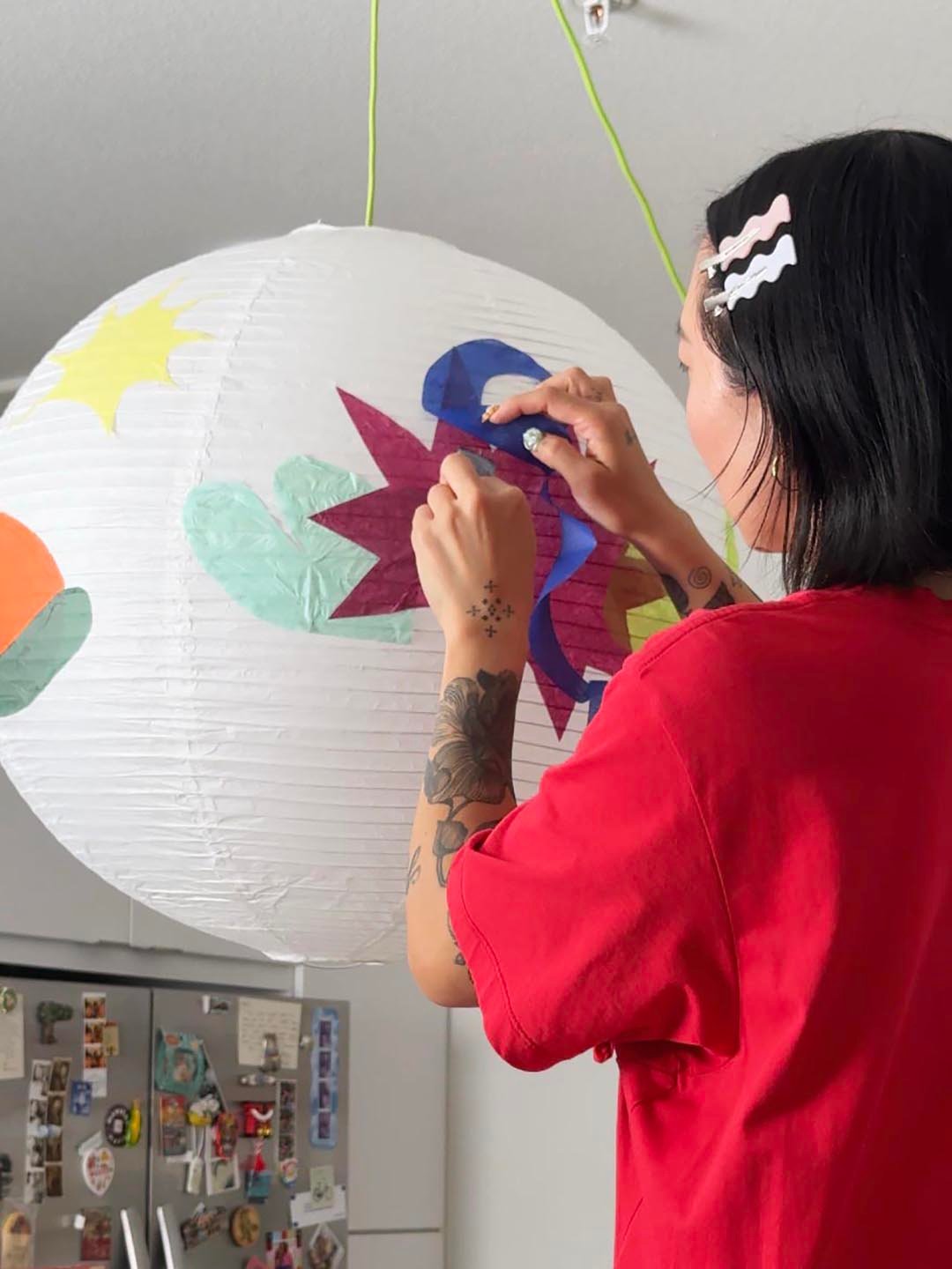 woman adhering paper to lantern
