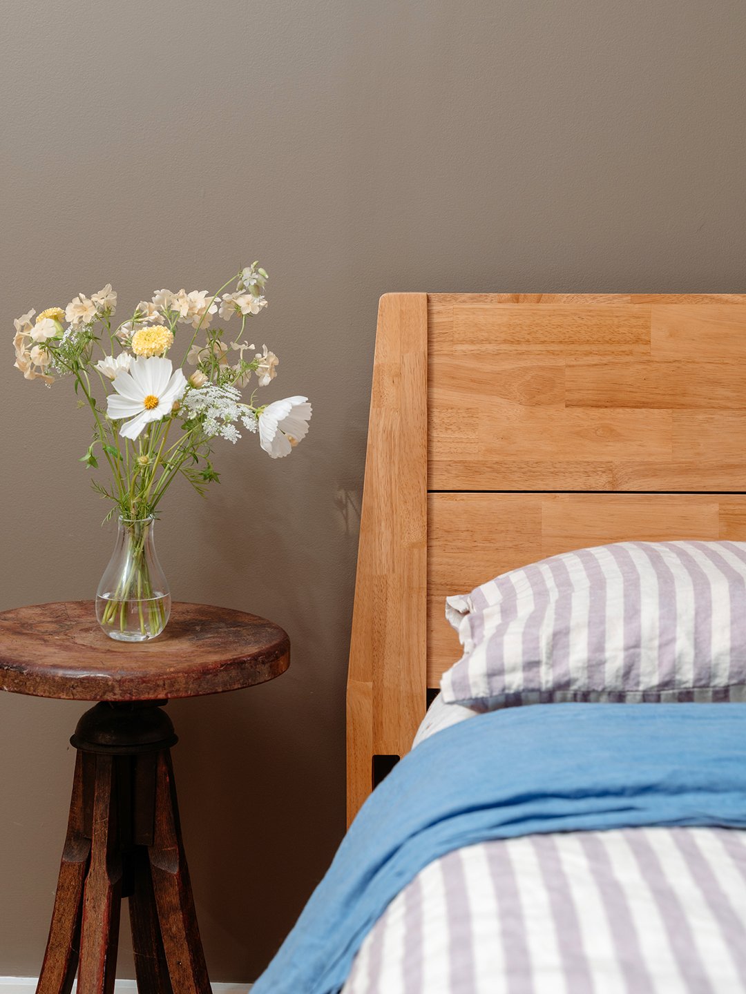 bedside table with flowers and wood headboard