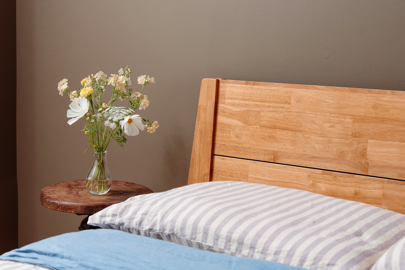 bedside table with flowers and wood headboard