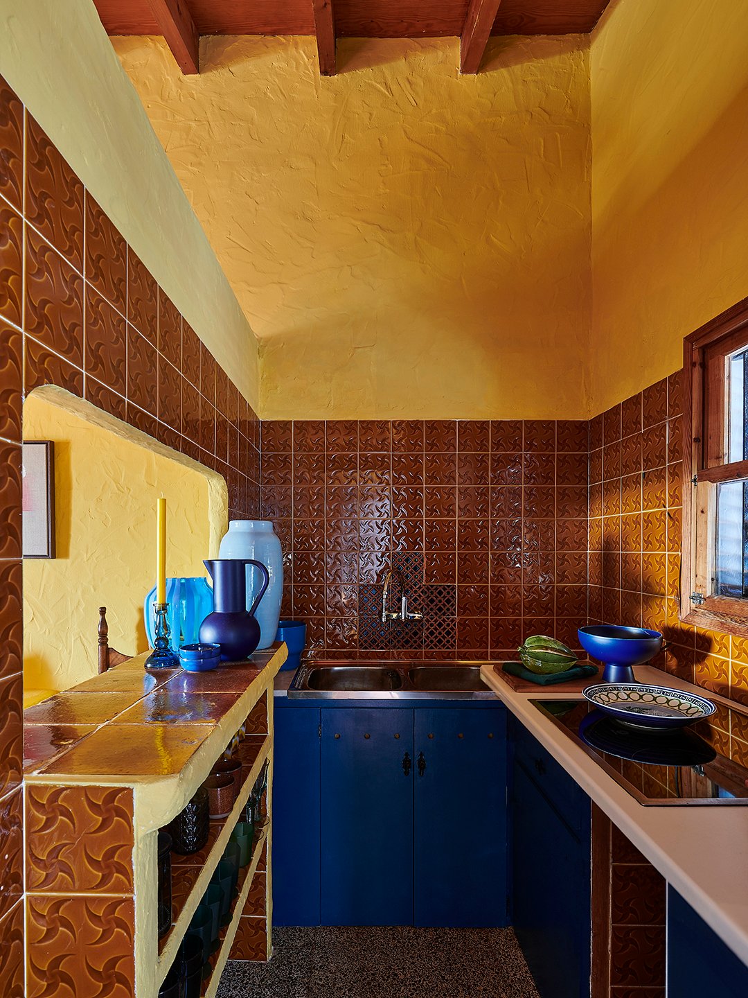 yellow kitchen with brown tile and blue cabinets