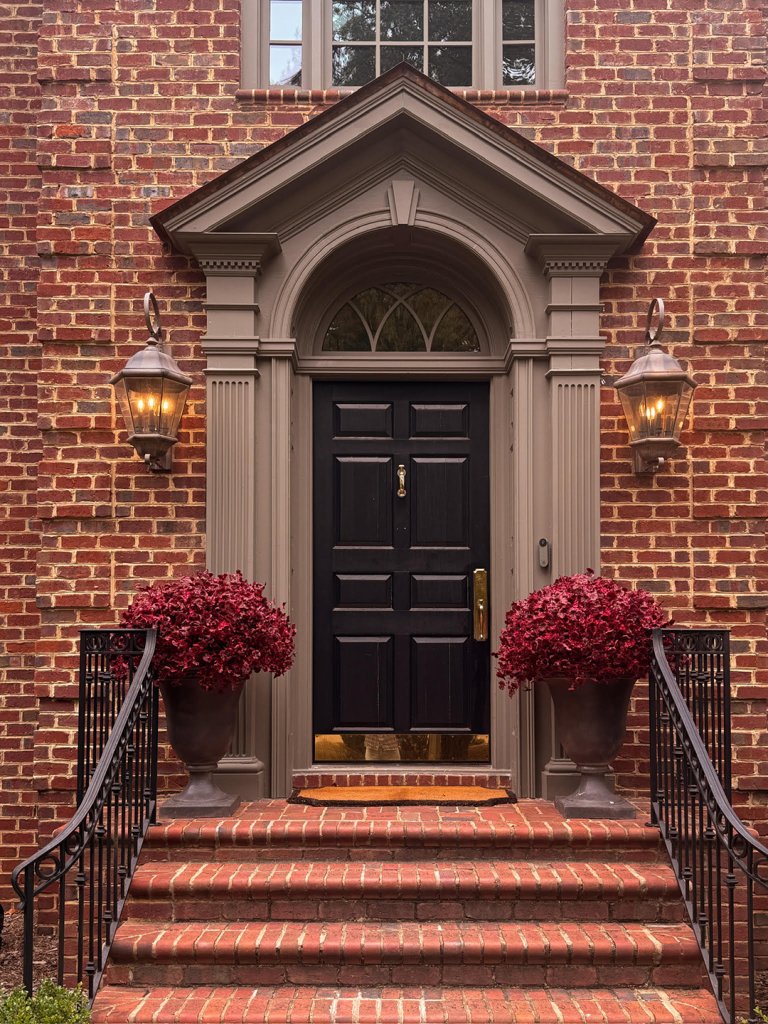 brick home with red mums in pots by front doorCourtesy of Chris Loves Julia