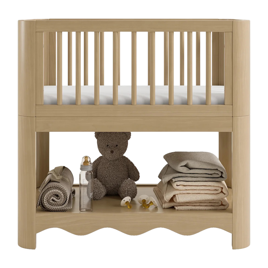 Wood bassinet with storage below with teddy bear and folded soft baby goods.