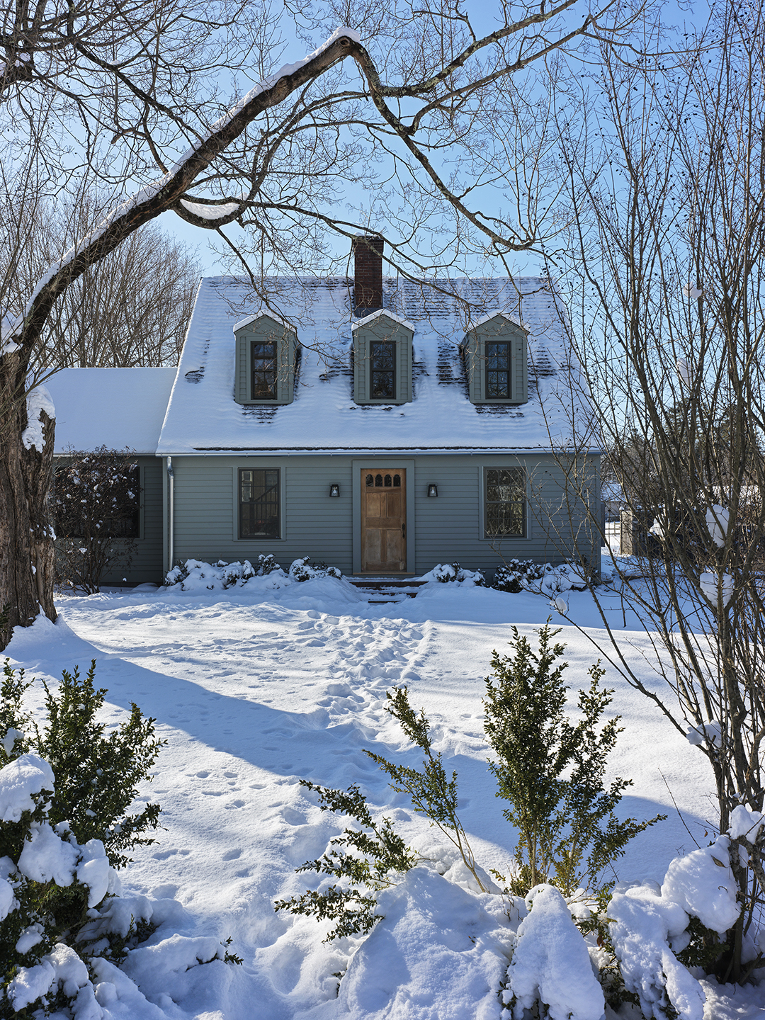 exterior of a blue cape cod house in the snow
