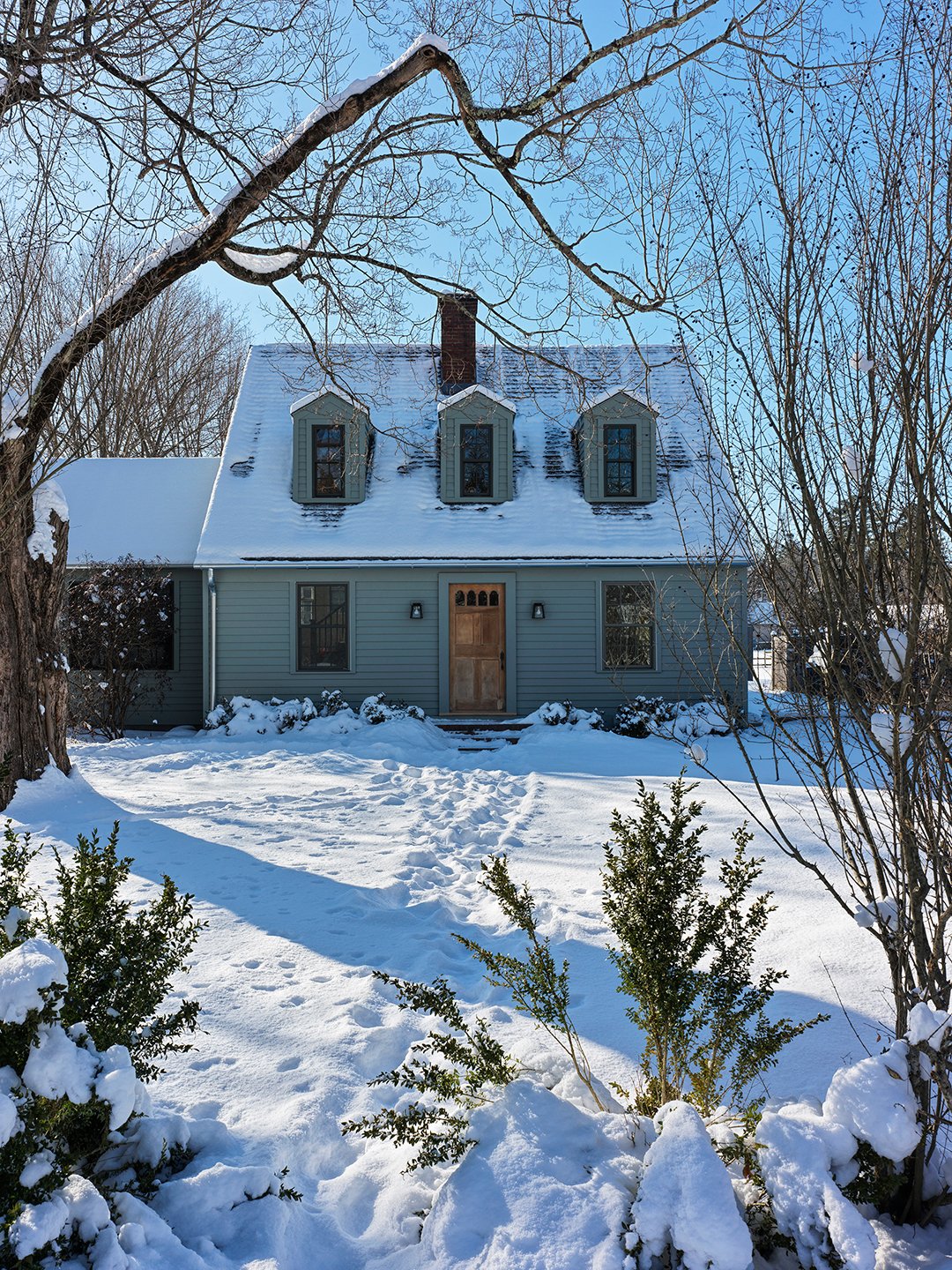 exterior of a blue cape cod house in the snow